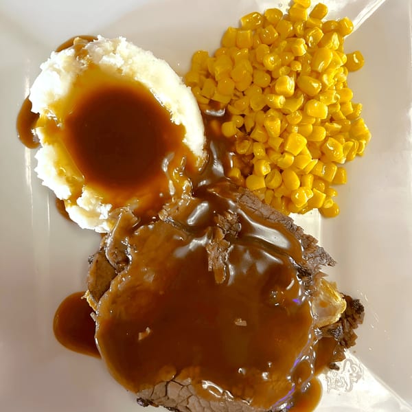Fresh Horses Saloon's roast beef with gravy, mashed potatoes, and corn on a white plate.
