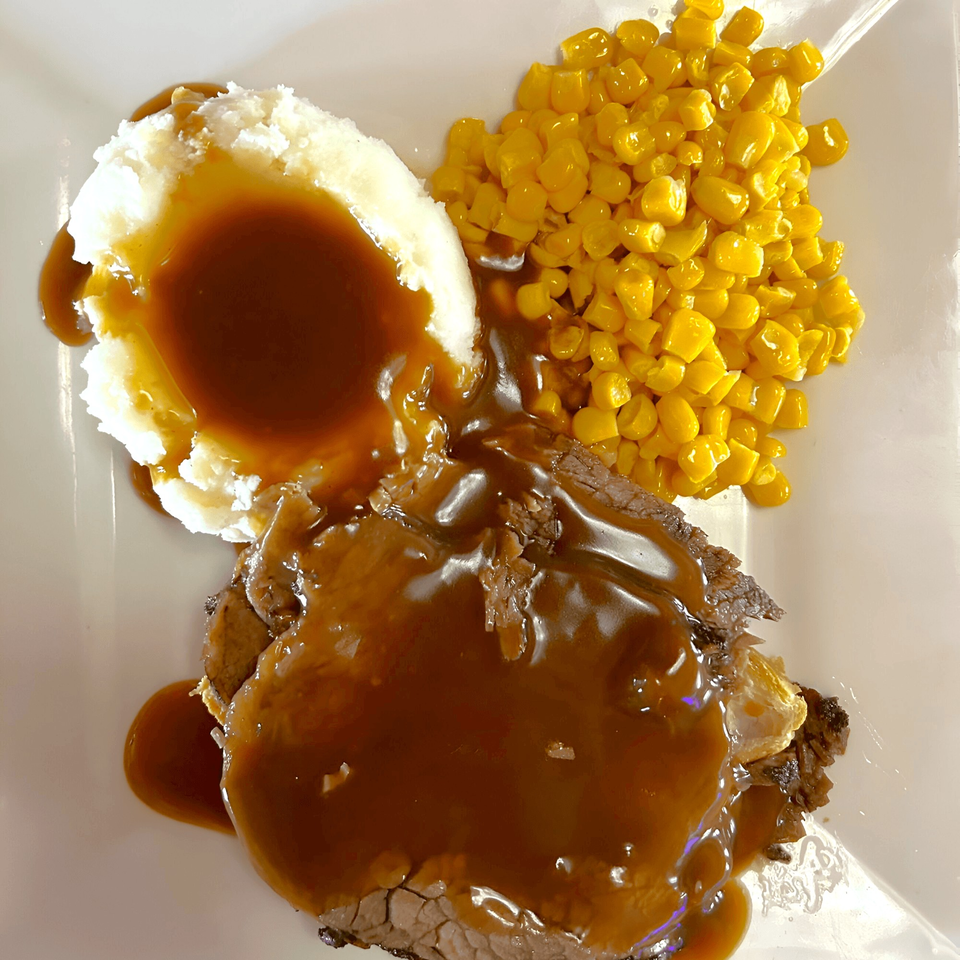 Fresh Horses Saloon's roast beef with gravy, mashed potatoes, and corn on a white plate.