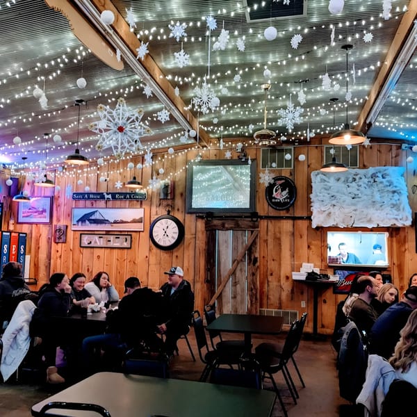 Diners seated at tables in Fresh Horses Saloon, decorated with string lights and snowflakes.