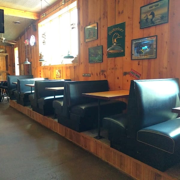 Interior of Fresh Horses Saloon with black booths, wooden walls, and duck-themed decor.