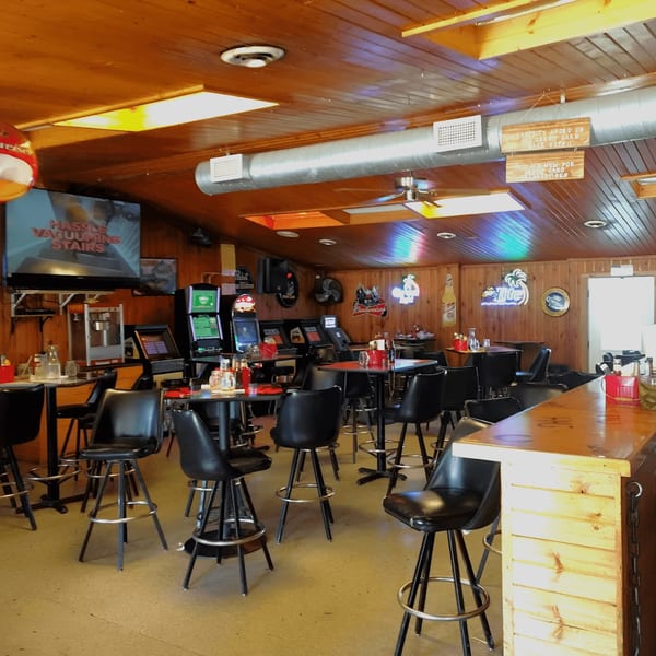 Interior of Fresh Horses Saloon, with bar stools, tables, arcade games, and neon signs.